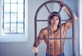 Suntanned muscular male in blue jeans posing.