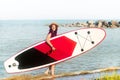 Sup boarding. A woman in a hat walks with a sup board.