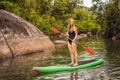 SUP Stand up paddle board woman paddle boarding on lake standing happy on paddleboard on blue water. Action Shot of Royalty Free Stock Photo