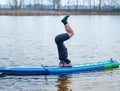 SUP YOGA, a man in a wetsuit doing yoga on a cloudy day, headstand on a paddle Board Royalty Free Stock Photo