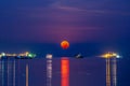 Super blood moon over Sriracha harbor with vessel cargo container ship on the sea water surface . night scene shot Royalty Free Stock Photo