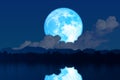 Super blue worm blue moon rise back silhouette mountain blur dark cloud on the night sky and reflection on water surface