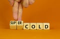 Super cold symbol. Doctor turns wooden cubes and changes concept words cold to super cold. Beautiful orange table, orange