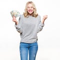 Super excited young woman in grey sweater and jeans holding bunch of Euro banknotes, clinching fists, celebrating.