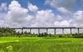 Super fast train crosses long viaduct at scenic location of green fields on Konkan Railway route Royalty Free Stock Photo