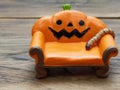 Super or giant worm crawling on orange miniature ceramic pumpkin couch or sofa over dark wooden surface