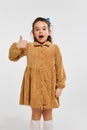 Super good. Beautiful little cute girl, kid in stylish dress emotionally posing against grey studio background. Concept Royalty Free Stock Photo