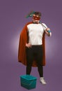 Super hero cleaner professional. Confidence man in red superhero costume with bucket and a mop stands on grape purple Royalty Free Stock Photo