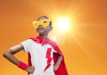 Super kid in red cape and yellow mask standing with hand on hip against bright sunlight Royalty Free Stock Photo