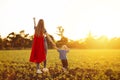 Super mom and her son walk forward holding hands. Cheerful family, a woman in a red raincoat as a superhero