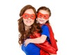 super mother piggybacking adorable daughter in mask and cloak and smiling at camera