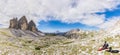 Super Panorama of the mountain ridge of Tre Cime di Lavaredo and resting tourist with his dog