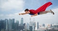 Man in red superhero cape flying in air over city Royalty Free Stock Photo