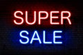 Super sale. Neon sign with luminous letters of red and blue on a black brick wall