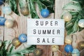 Super Summer Sale text in light box with LED cotton balls decorated on wooden background