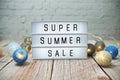 Super Summer Sale text in light box with LED cotton balls decorated on wooden background