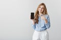 Super useful device. Studio shot of pleased good-looking female student with blond hair in blue-collar shirt, showing