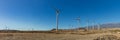 Super wide panorama of Wind power stations. A row of turbines near the seashore. Wind farm eco field. Eolic park with blue sky in Royalty Free Stock Photo