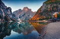 Superb autumn view of Braies Pragser Wildsee lake with boats and fishing dock.