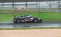 Supercar Honda racing on wet raining asphalt track circuit spraying water