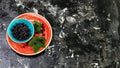 Superfoods antioxidant of indian mapuche. Bowl of fresh maqui berry on blue background, top view Authentic lifestyle image