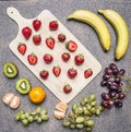 Superfoods and healthy lifestyle or detox diet food concept bananas, strawberries, light dark grapes, kiwi and tangerine on a