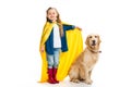 Supergirl in yellow cape standing with golden retriever beside