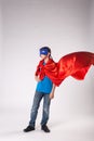 Superhero child in red cape fluttering on wind