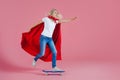 Superhero on a skateboard. Funny young woman in the image of a superhero to the rescue