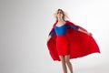 Superhero Woman. Young and beautiful blonde in image of superheroine in red Cape growing