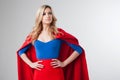 Superhero Woman. Young and beautiful blonde in image of superheroine in red Cape growing