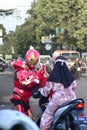 A superhuman actor standing iron man greets a small child on a motorbike on a highway near a traffic light Royalty Free Stock Photo