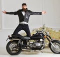 Superiority concept. Hipster biker brutal in leather jacket on motorcycle enjoying richness. Man, bearded biker in Royalty Free Stock Photo