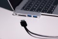 Supermacro photo shot focused on a black usb a cable, usb to usb-c adapter and laptop are strongly out of focus
