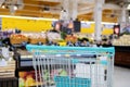 Supermarket aisle with empty blue shopping cart Royalty Free Stock Photo