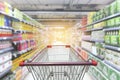Supermarket aisle with empty red shopping cart with customer defocus background Royalty Free Stock Photo
