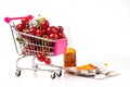 A supermarket cart is filled with ripe red cherries next to the medicines. A concept on the topic of a healthy lifestyle Royalty Free Stock Photo