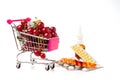 A supermarket cart is filled with ripe red cherries next to the medicines. A concept on the topic of a healthy lifestyle Royalty Free Stock Photo