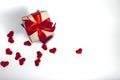 A supermarket cart filled to the brim with red hearts and a gift box wrapped in kraft paper and tied with a red ribbon on a white Royalty Free Stock Photo