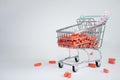 supermarket cart full of orange pills and a tape measure on a white background.