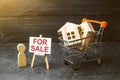 Supermarket cart with houses and man with a poster for sale. The concept of selling a home, real estate services or buying from Royalty Free Stock Photo