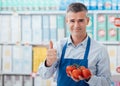 Supermarket clerk holding tomatoes Royalty Free Stock Photo