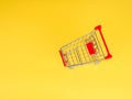 supermarket trolley on yellow background, empty, Concept of shopping. Copy space for advertisement.