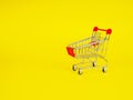 supermarket trolley on yellow background, empty, Concept of shopping. Copy space for advertisement.