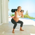 Supermom in training. a pregnant woman working out with a sand bag on the patio at home. Royalty Free Stock Photo