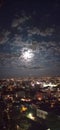 Supermoon, a full moon that hides behind clouds and above the city
