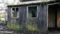 A supernatural ghost concept. A mysterious blurred, hooded figure, moving past a window in an abandoned, ruined home