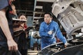 Supervisor engineer is teaching mechanic workers about car repair at a garage. Royalty Free Stock Photo