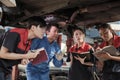 Supervisor engineer is teaching mechanic workers about car repair at a garage. Royalty Free Stock Photo