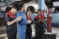 A supervisor engineer is training mechanic workers about car repair at a garage. Royalty Free Stock Photo